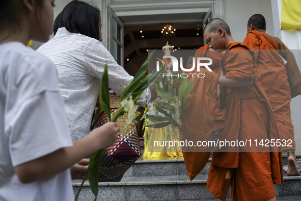 Thais are offering flowers to Buddhist monks during a floral merit-making ceremony, known as 'tak bat dok mai', at Rama IX Golden Jubilee Te...