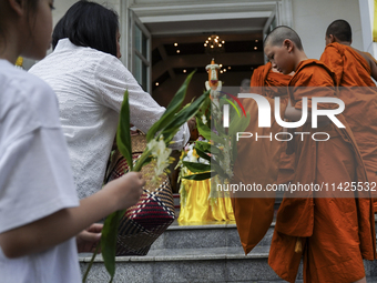 Thais are offering flowers to Buddhist monks during a floral merit-making ceremony, known as 'tak bat dok mai', at Rama IX Golden Jubilee Te...