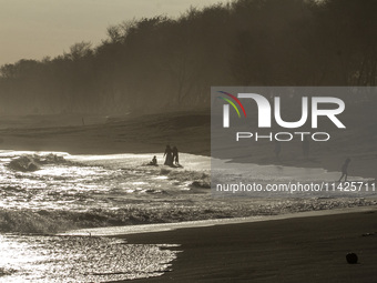 People are visiting Goa Cemara Beach, one of the tourist destinations in Bantul, Yogyakarta, Indonesia, during sunset on July 21, 2024. (