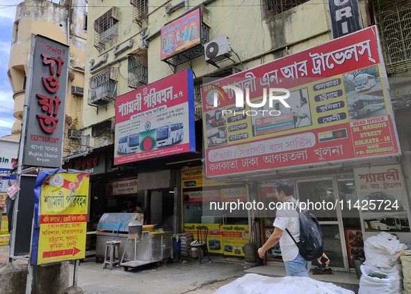 People are passing next to an International Bus transport office in Kolkata, India, on July 21, 2024. International Bus Service is stopping...