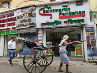 A hand-pulled rickshaw is passing next to an International Bus transport office in Kolkata, India, on July 21, 2024. International Bus Servi...