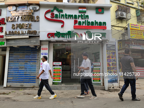 People are passing next to an International Bus transport office in Kolkata, India, on July 21, 2024. The International Bus Service is stopp...