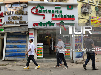 People are passing next to an International Bus transport office in Kolkata, India, on July 21, 2024. The International Bus Service is stopp...