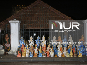 A girl is selling clay idols of Lord Krishna along the roadside just outside the historic Sree Padmanabhaswamy Temple during the night of th...