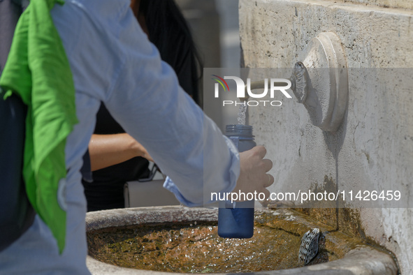 Tourists are filling up water bottles from a public fountain in Saint Peter, Rome, Italy, on July 21, 2024. 