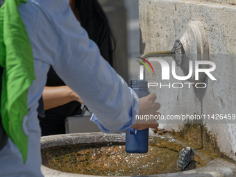 Tourists are filling up water bottles from a public fountain in Saint Peter, Rome, Italy, on July 21, 2024. (