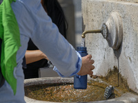 Tourists are filling up water bottles from a public fountain in Saint Peter, Rome, Italy, on July 21, 2024. (