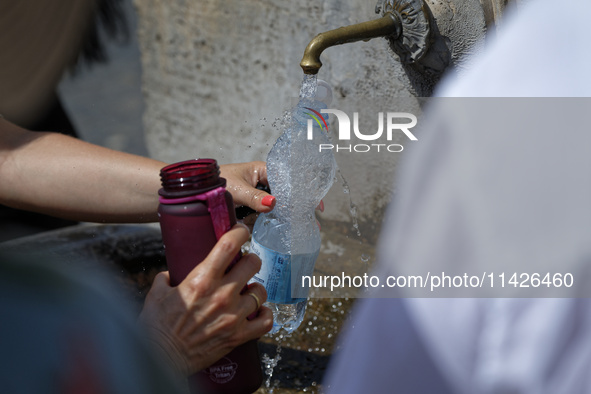 Tourists are filling up water bottles from a public fountain in Saint Peter, Rome, Italy, on July 21, 2024. 