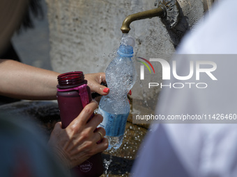 Tourists are filling up water bottles from a public fountain in Saint Peter, Rome, Italy, on July 21, 2024. (