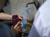 Tourists are filling up water bottles from a public fountain in Saint Peter, Rome, Italy, on July 21, 2024. (