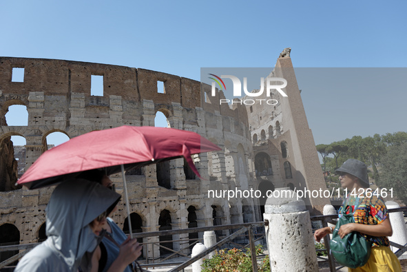 Tourists are sheltering from the sun and heat wave under umbrellas in front of the Colosseum in Rome, Italy, on July 21, 2024. 