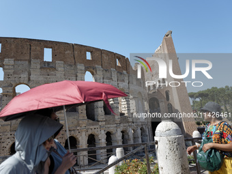 Tourists are sheltering from the sun and heat wave under umbrellas in front of the Colosseum in Rome, Italy, on July 21, 2024. (