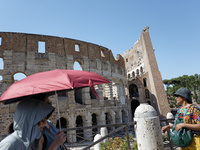 Tourists are sheltering from the sun and heat wave under umbrellas in front of the Colosseum in Rome, Italy, on July 21, 2024. (