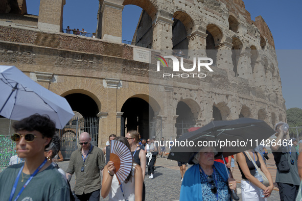 Tourists are sheltering from the sun and heat wave under umbrellas in front of the Colosseum in Rome, Italy, on July 21, 2024. 