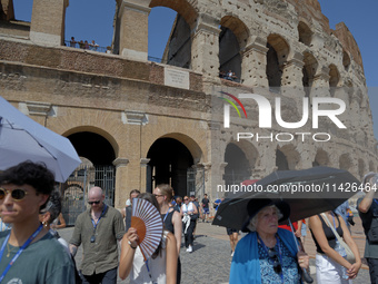 Tourists are sheltering from the sun and heat wave under umbrellas in front of the Colosseum in Rome, Italy, on July 21, 2024. (