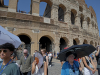 Tourists are sheltering from the sun and heat wave under umbrellas in front of the Colosseum in Rome, Italy, on July 21, 2024. (