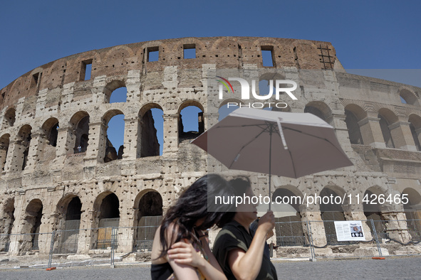 Tourists are sheltering from the sun and heat wave under umbrellas in front of the Colosseum in Rome, Italy, on July 21, 2024. 