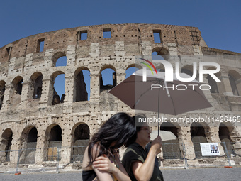 Tourists are sheltering from the sun and heat wave under umbrellas in front of the Colosseum in Rome, Italy, on July 21, 2024. (