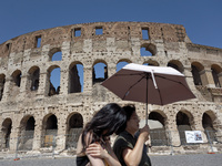 Tourists are sheltering from the sun and heat wave under umbrellas in front of the Colosseum in Rome, Italy, on July 21, 2024. (