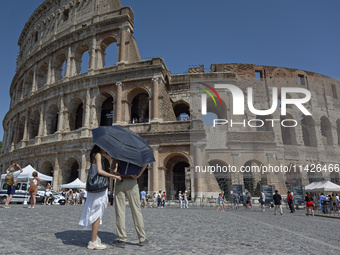 Tourists are sheltering from the sun and heat wave under umbrellas in front of the Colosseum in Rome, Italy, on July 21, 2024. (