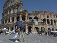 Tourists are sheltering from the sun and heat wave under umbrellas in front of the Colosseum in Rome, Italy, on July 21, 2024. (