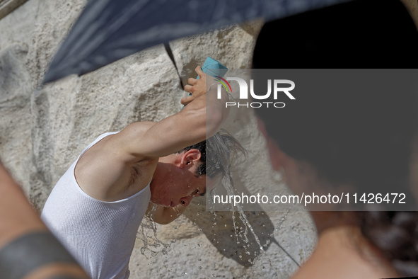 Tourists are trying to cool off with the help of fountains in the streets in Rome, Italy, on July 21, 2024, as the city is on alert for extr...