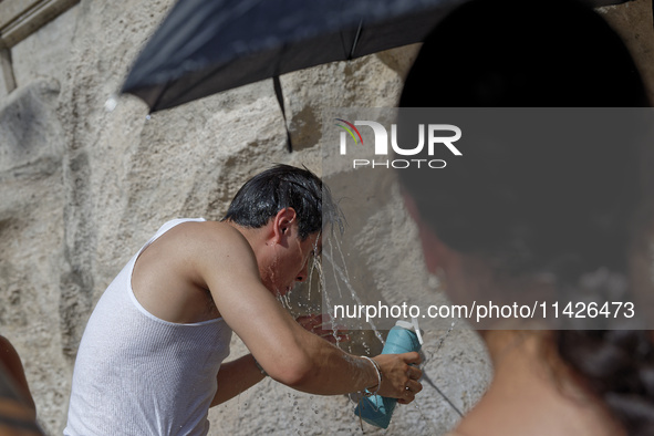 Tourists are trying to cool off with the help of fountains in the streets in Rome, Italy, on July 21, 2024, as the city is on alert for extr...