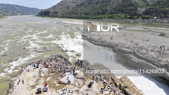 Tourists are visiting Hukou Waterfall on the Yellow River at the junction of Yichuan county and Ji county in North China's Shaanxi province,...