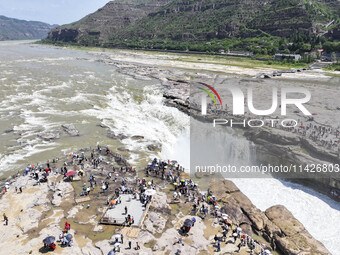 Tourists are visiting Hukou Waterfall on the Yellow River at the junction of Yichuan county and Ji county in North China's Shaanxi province,...