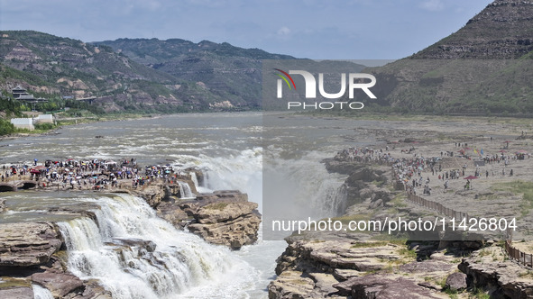 Tourists are visiting Hukou Waterfall on the Yellow River at the junction of Yichuan county and Ji county in North China's Shaanxi province,...