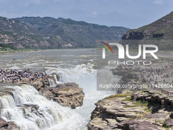 Tourists are visiting Hukou Waterfall on the Yellow River at the junction of Yichuan county and Ji county in North China's Shaanxi province,...