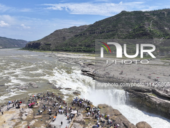 Tourists are visiting Hukou Waterfall on the Yellow River at the junction of Yichuan county and Ji county in North China's Shaanxi province,...