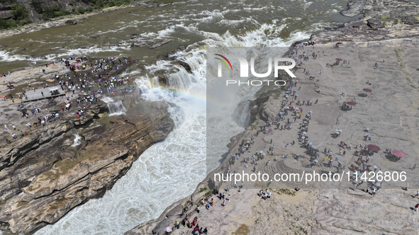 Tourists are visiting Hukou Waterfall on the Yellow River at the junction of Yichuan county and Ji county in North China's Shaanxi province,...