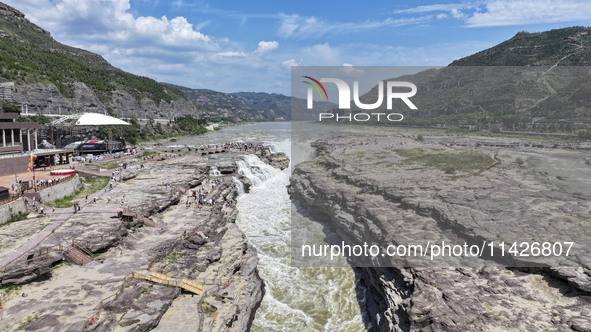 Tourists are visiting Hukou Waterfall on the Yellow River at the junction of Yichuan county and Ji county in North China's Shaanxi province,...