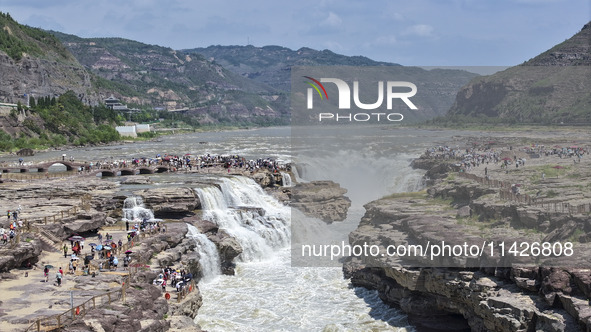 Tourists are visiting Hukou Waterfall on the Yellow River at the junction of Yichuan county and Ji county in North China's Shaanxi province,...