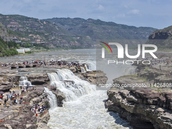 Tourists are visiting Hukou Waterfall on the Yellow River at the junction of Yichuan county and Ji county in North China's Shaanxi province,...