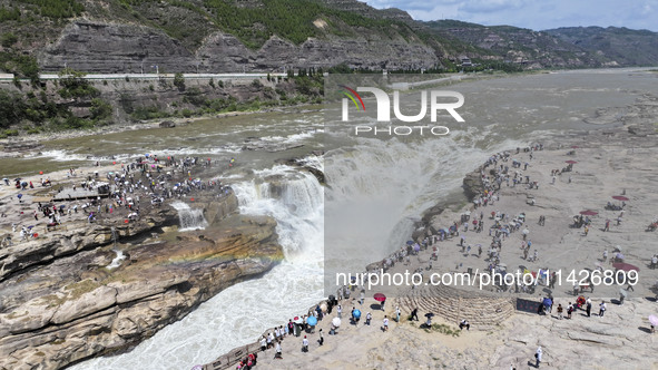 Tourists are visiting Hukou Waterfall on the Yellow River at the junction of Yichuan county and Ji county in North China's Shaanxi province,...