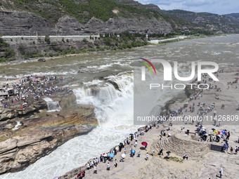 Tourists are visiting Hukou Waterfall on the Yellow River at the junction of Yichuan county and Ji county in North China's Shaanxi province,...