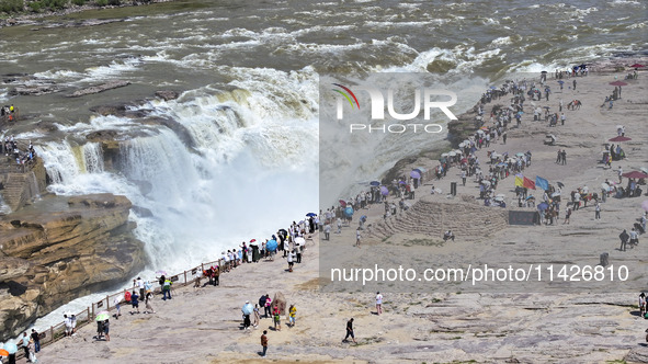 Tourists are visiting Hukou Waterfall on the Yellow River at the junction of Yichuan county and Ji county in North China's Shaanxi province,...