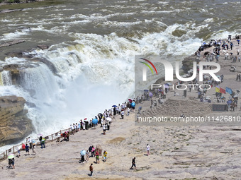 Tourists are visiting Hukou Waterfall on the Yellow River at the junction of Yichuan county and Ji county in North China's Shaanxi province,...