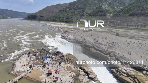 Tourists are visiting Hukou Waterfall on the Yellow River at the junction of Yichuan county and Ji county in North China's Shaanxi province,...