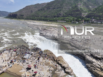 Tourists are visiting Hukou Waterfall on the Yellow River at the junction of Yichuan county and Ji county in North China's Shaanxi province,...