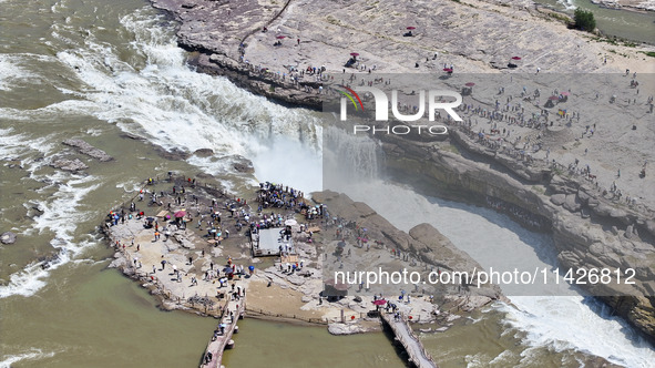 Tourists are visiting Hukou Waterfall on the Yellow River at the junction of Yichuan county and Ji county in North China's Shaanxi province,...