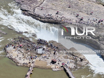 Tourists are visiting Hukou Waterfall on the Yellow River at the junction of Yichuan county and Ji county in North China's Shaanxi province,...