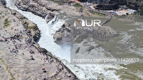 Tourists are visiting Hukou Waterfall on the Yellow River at the junction of Yichuan county and Ji county in North China's Shaanxi province,...