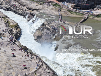 Tourists are visiting Hukou Waterfall on the Yellow River at the junction of Yichuan county and Ji county in North China's Shaanxi province,...