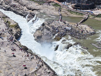 Tourists are visiting Hukou Waterfall on the Yellow River at the junction of Yichuan county and Ji county in North China's Shaanxi province,...