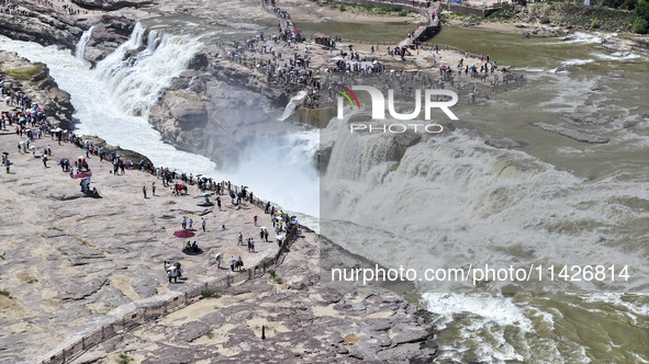 Tourists are visiting Hukou Waterfall on the Yellow River at the junction of Yichuan county and Ji county in North China's Shaanxi province,...