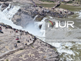 Tourists are visiting Hukou Waterfall on the Yellow River at the junction of Yichuan county and Ji county in North China's Shaanxi province,...