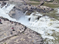 Tourists are visiting Hukou Waterfall on the Yellow River at the junction of Yichuan county and Ji county in North China's Shaanxi province,...